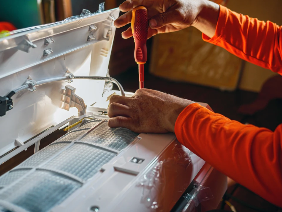 Main d'un technicien utilise un tournevis pour serrer les écrous de l'ensemble de climatisation, des techniciens de l'air conditionné Préparez-vous à installer un nouveau climatiseur dans les maisons.